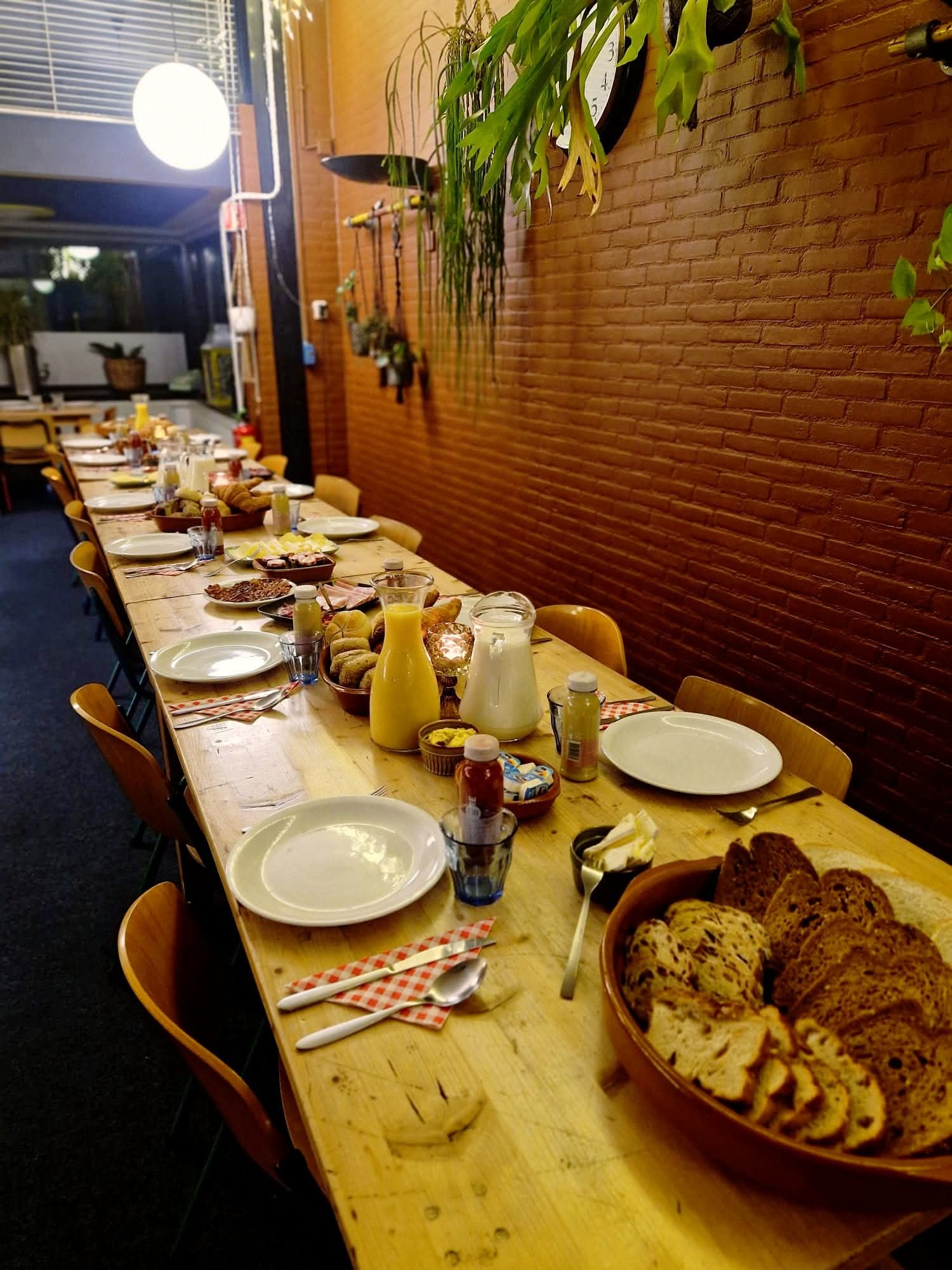 Een lange gedekte tafel met brood, sap en gebak, klaar voor een catering bij Eetcafé Wiegman