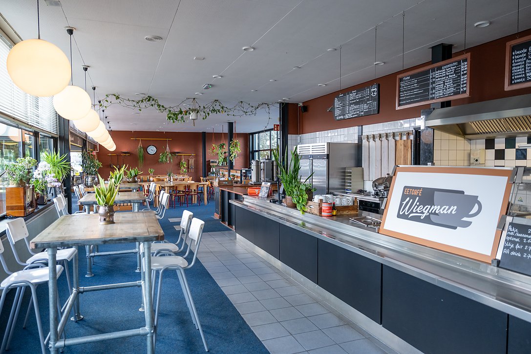 het interieur van Eetcafé Wiegman met de bollampen, de lange tafels en de balie