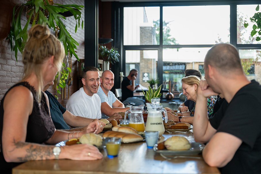 gasten lunchen aan de lange tafel bij Eetcafé Wiegman