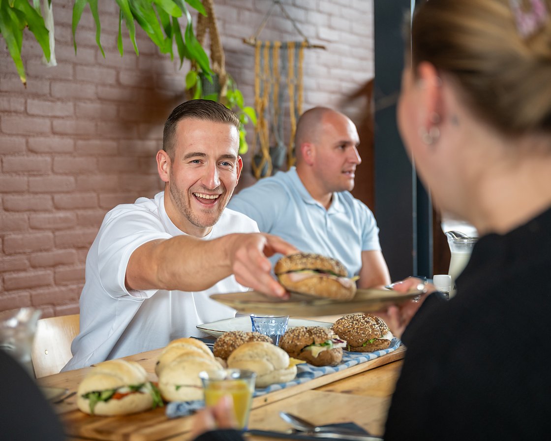 een belegd broodje wordt aangereikt aan tafel